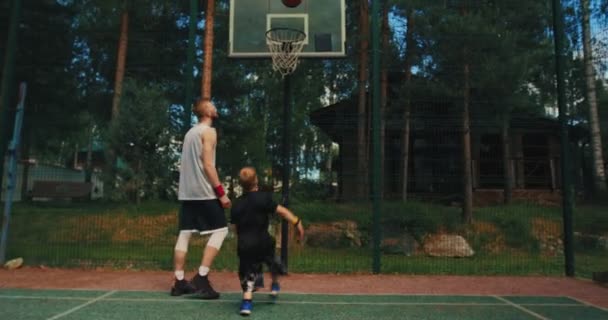 Man basket instruktör utbildning pojke spelare scoring båge kasta boll i korg på basketplan utomhus — Stockvideo