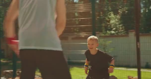 Ruční záběr mladého muže basketbalista dribling míč, pohybující se kolem obránce dítě chlapce při hraní streetball — Stock video