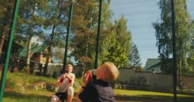 Küçük sporcu çocuk basketbol potasına top atıyor dışarıda antrenman yapıyor, baba kameraya video çekiyor.