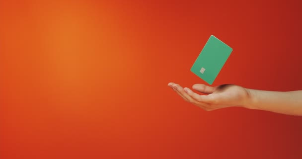 Vrouwelijke hand houdt zwevende template mockup bank credit card met online service geïsoleerd op oranje achtergrond — Stockvideo