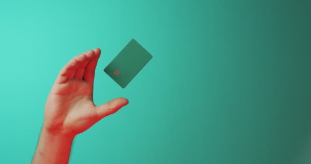 Close-up male hand and levitating template mockup bank credit card isolated on green background. Copy space — Stock Video