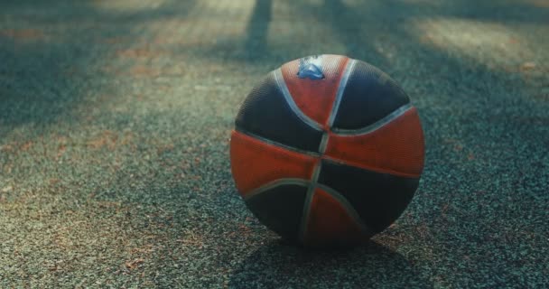 Close-up schot met focus van de bal liggend op de grond op basketbalveld. Man pikt bal op en loopt dan weg. — Stockvideo