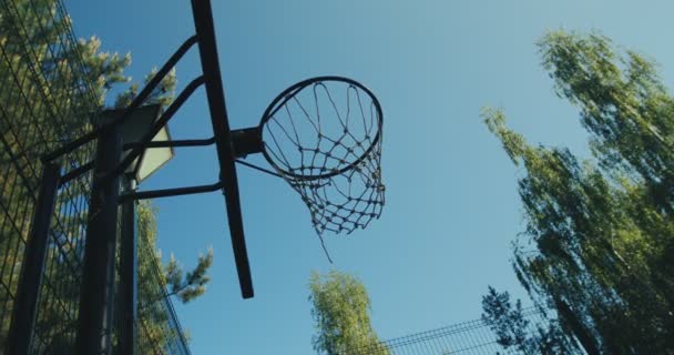 Баскетбольная площадка на природе. Мяч, брошенный в баскетбольное кольцо, пролетает мимо на фоне летнего неба. Цель, концепция цели — стоковое видео