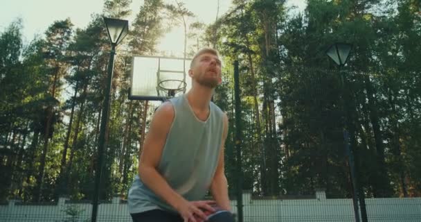 Профессиональный баскетболист летом капает и забрасывает мяч на баскетбольной площадке под открытым небом — стоковое видео