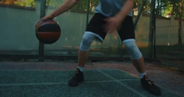 Erkek basketbolcu bacaklarının arasında top sürüyor, basketbol sahasında basketbol antrenmanı sırasında basket atıyor. — Stok video