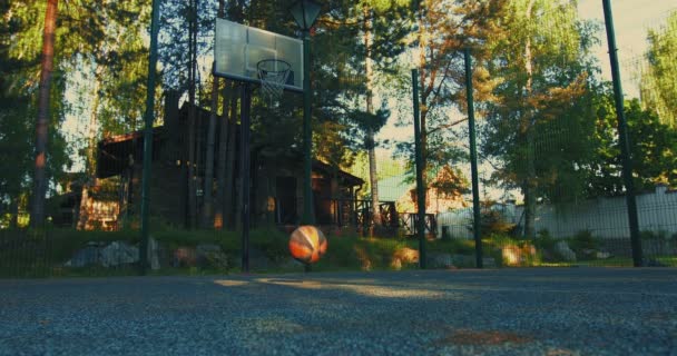 Bola de basquete rolando e saltando no campo de basquete chão ao ar livre no verão. Conceito de treino ao ar livre — Vídeo de Stock