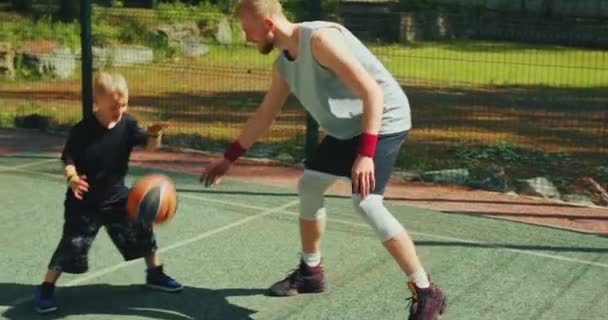 Jogador de basquete pai formação filho para driblar na quadra de basquete ao ar livre no verão. Família feliz esportiva — Vídeo de Stock