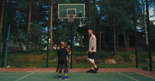Männlicher Basketballspieler Vater trainiert Jungen seinen Sohn, um Basketballkorb auf Basketballplatz im Freien zu werfen — Stockvideo