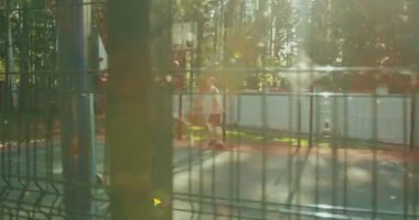 Erkek basketbolcu sahada güneş ışığında açık havada antrenman yapıyor. Dışarıda aktif egzersiz