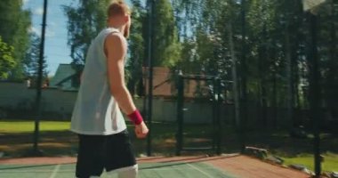 Erkek basketbolcu sporcu, sahada sahada güneş ışığında basket atıyor.