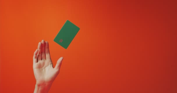 Mano femminile e modello levitante mockup carta di credito bancario isolato su sfondo arancione, spazio di copia — Video Stock