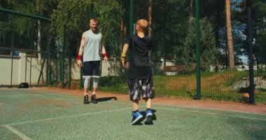 Basketbolcu adam ve çocuk antrenmandan önce ısınıyorlar. Sportif aile babası, oğlu basketbol sahasında antrenman yapıyor. 