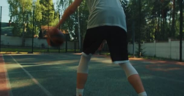 Joueur de basket-ball masculin pratiquant la manipulation des balles, dribble ball entre les jambes, cerceau de notation sur le terrain extérieur — Video