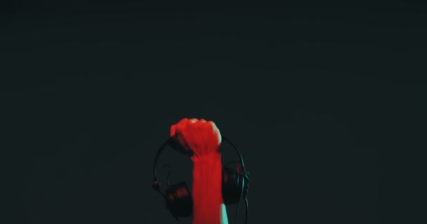 Male hand with headphones raising up in colorful light. Close-up. Music and protest concept — Stok video