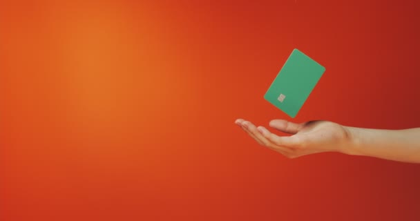 Close up female hand holds levitating template mockup Bank credit card with online service isolated on orange background — Stock Video