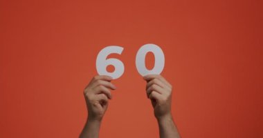 Number sixty in hands. Man showing digits, 60 made of carved paper for voting or mathematics learning