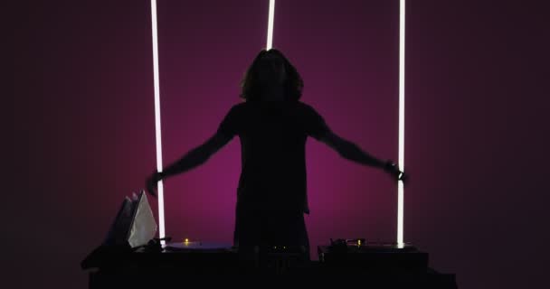 Silhouette of male deejay dancing, performing in nightclub at dj console, rocking party up. Nightlife concept — Stockvideo