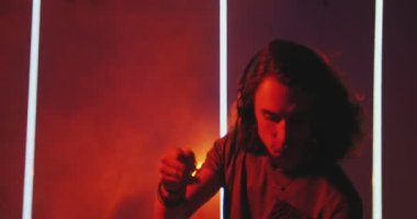 Dancing deejay cool guy wearing headphones lights up at the disco during performance in nightclub. Modern rave