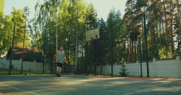 Basketball player young handsome guy training on court outdoors on nature in summer — Stock Video