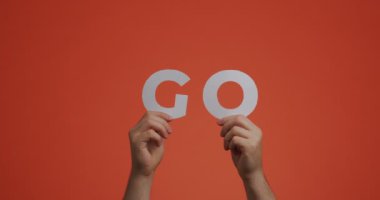 Hands raising up showing word go of english language. Man shows motivational phrase made of carved paper for blog