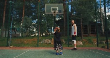 Erkek basketbol hocası, erkek oyuncu antrenörü basketbol sahasında potaya basket atıyor.