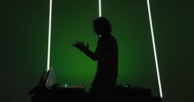 Silhouette of Dj performing in nightclub, dancing at mixer controller, rocking party up. Nightlife concept
