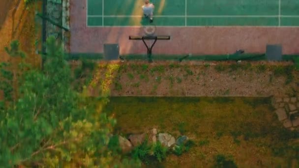 Lanzamiento aéreo de cancha de baloncesto. Vista aérea del jugador de baloncesto acercándose, lanzando pelota en el aro al aire libre — Vídeos de Stock