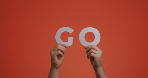 Hands raising up showing word go of english language. Man shows motivational phrase made of carved paper for blog — Vídeo de Stock