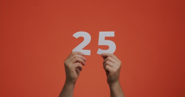 Numer 25 w rękach. Mężczyzna pokazuje cyfry, 25 wykonane z rzeźbionego papieru do głosowania lub nauki matematyki — Wideo stockowe