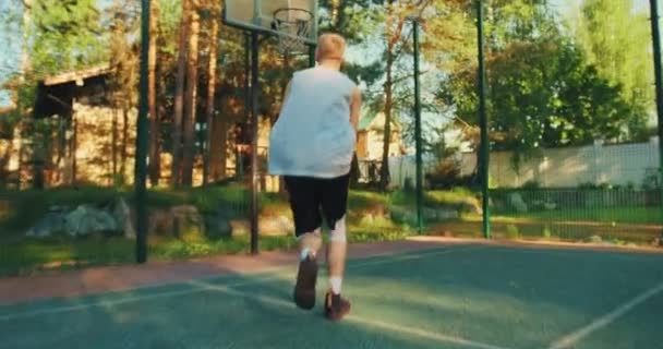 Rückansicht eines jungen Mannes, der erfolgreich Basketball spielt und einen Ball zum Korb wirft. Zeitlupenschuss — Stockvideo