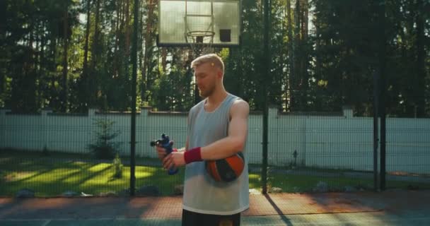 Professionele basketbalspeler koele jonge man drinken water tijdens de training op basketbalveld in het zonlicht buiten — Stockvideo