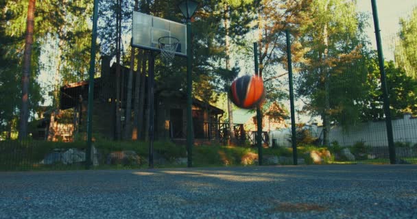 Basketball ball bouncing on basketball court ground outdoor in summertime. Outdoors workout concept — Stock Video