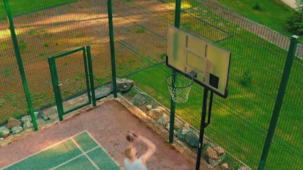 Vue du dessus du joueur de basket approchant, cerceau de notation sur le terrain de basket en plein air dans la lumière du soleil — Video