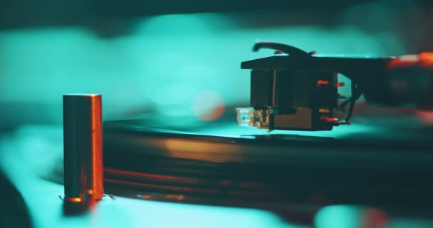 Vinylskivan snurrar på spelaren. Vändbar stylus på skiva, närbild i färgglada neon studio ljus. — Stockvideo