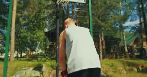 Jogador de basquete pai levantando o filho a mãos, ajudando menino marcando aro na quadra de basquete ao ar livre na luz do sol — Vídeo de Stock