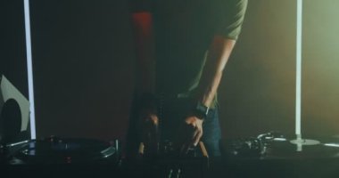 DJ 'lik yapan, uzun saçlı, kulaklıklı genç adam DJ' in pikabında müzik dinleyip dans ediyor. Gece hayatı partisi