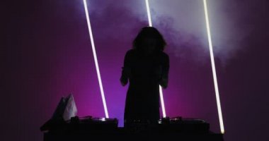 Modern erkek DJ 'in silueti gece kulübündeki DJ konsolunda vinil çalıyor. Gece hayatı ve parti.