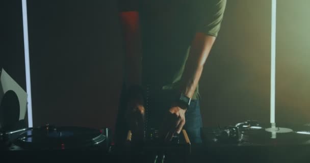 DJ 'lik yapan, uzun saçlı, kulaklıklı genç adam DJ' in pikabında müzik dinleyip dans ediyor. Gece hayatı partisi — Stok video