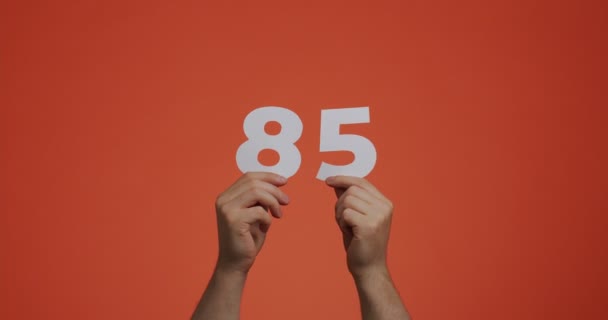Číslo osmdesát pět v rukou. Muž ukazující číslice, 85 z vyřezávaného papíru pro hlasování, matematiku učení nebo prodej