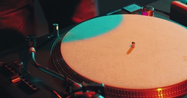 Deejay mengubah rekaman musik vinyl di meja putar dan bermain musik selama pesta, close-up, warna-warni cahaya — Stok Video