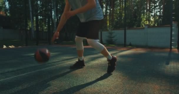 American basketball player in action with ball dribbling on basketball court outdoors, close up — Stock Video