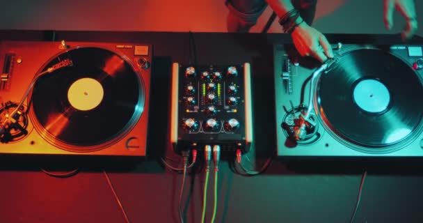 Deejay jouant de la musique électronique sur le bureau de contrôleur de mélangeur de DJ dans la soirée de boîte de nuit. Dj touchant vinyles, curseurs. Vue du dessus — Video