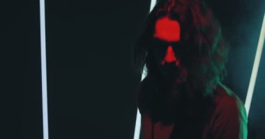 Dj 'lik yapan havalı çocuk gece kulübündeki performans sırasında diskoda sigara yakıyor. Modern parti. Renkli ışık