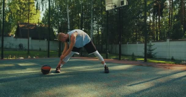 여름에 야외에서 경기를 하기 전에 법정에서 몸을 따뜻하게 하는 프로 스포츠 남성 미국 농구 선수 — 비디오