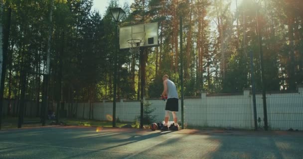 Mannelijke basketbalspeler drinken water en trow bal in hoepel tijdens de training buiten op basketbalveld — Stockvideo