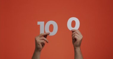 Yüz numara elinde. Oy vermek ya da matematik öğrenmek için oylanmış kağıttan yapılmış 100 haneli rakamlar gösteren bir adam.