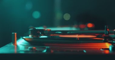 Renkli ışıkta DJ pikabında dönen vinil müzik plağı, yakın plan. Parti ve müzik konsepti