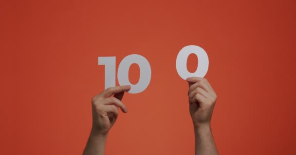 Nummer hundert in Händen. Mann zeigt Ziffern, 100 aus geschnitztem Papier zum Wählen oder Mathe-Lernen — Stockvideo