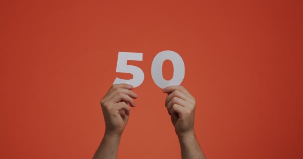 Numer pięćdziesiąt w rękach. Mężczyzna pokazuje cyfry, 50 wykonane z papieru rzeźbionego do głosowania lub nauki matematyki — Wideo stockowe