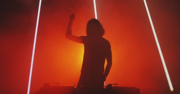 Hot dj rave. Silhouette of dancing deejay young guy rocking party up in red light in smoke in nightclub — Stock Video